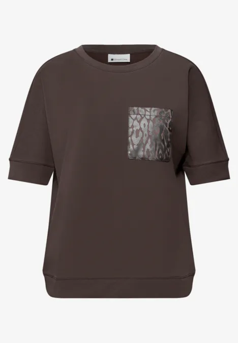 Dunkelbraunes, locker geschnittenes Shirt mit halblangen Ärmeln und gemusterter Brusttasche.